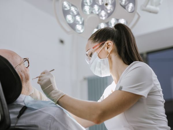 Medic stomatolog care consultă un pacient în cabinet