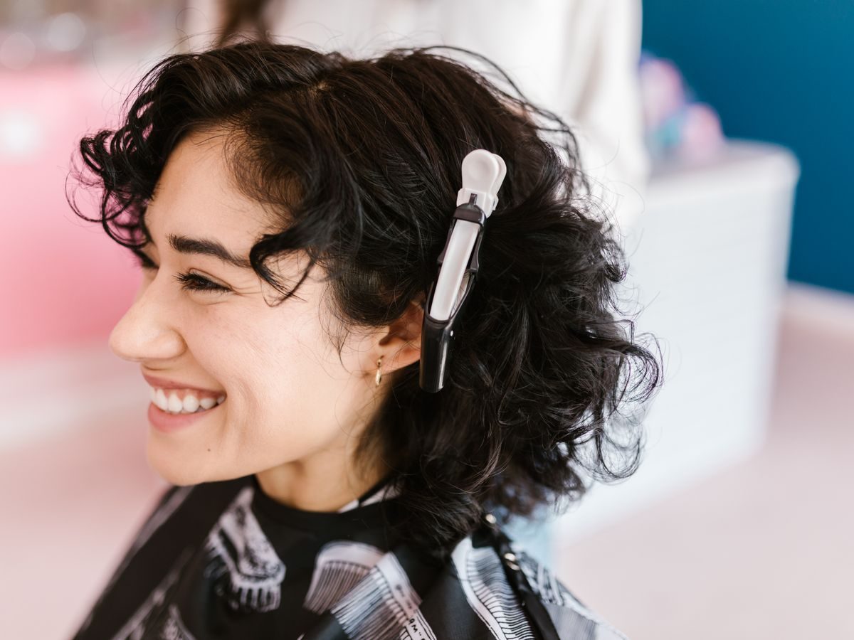 Hairstylist care aranjează părul unei cliente în salon